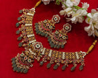 A broad floral necklace with red, green and clear accents, an ornate pendant and pale green drops.